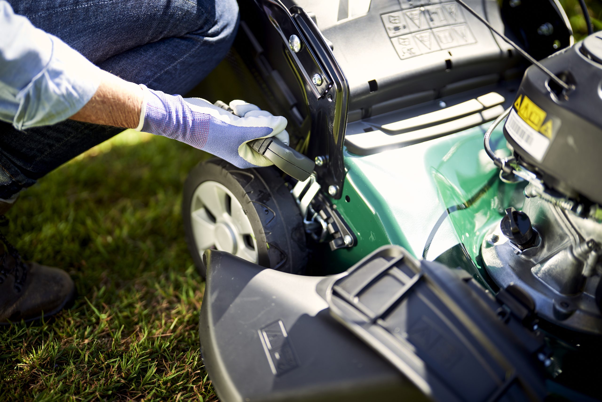 woman adjusting height of cut on lawnmower